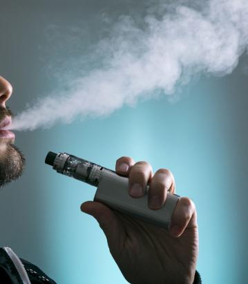 一个人的剪影vaping在蓝色背景前面